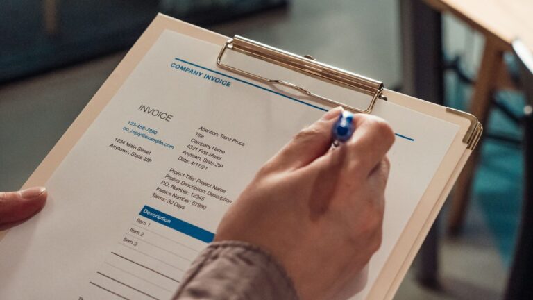 Hand holding a business invoice on a clipboard