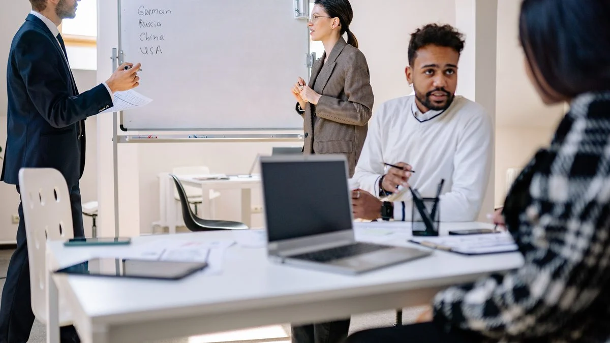Small team collaborating around laptops and a whiteboard in an office