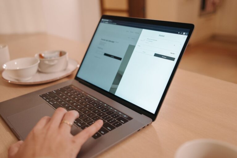 Person reviewing a website page on a laptop at a wooden desk
